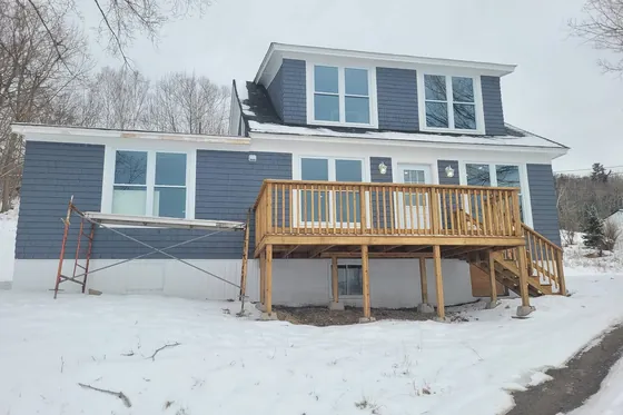 A house with new blue shingle siding and a newly built cedar deck and stairs